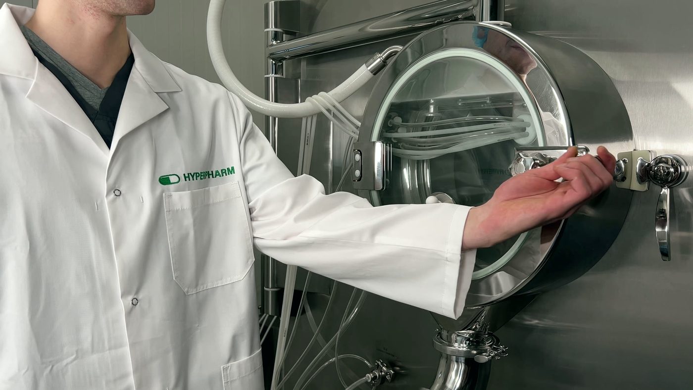 Tablet coating drum at the plant, an operator in a HYPERPHARM coat opening the door